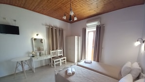 A bedroom with two beds, a desk, a chair, a mirror, and a ceiling light fixture. - DIAMOND VIEW (Lesvos)