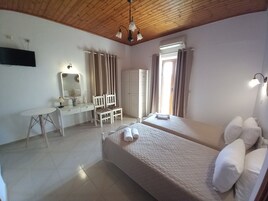 A bedroom with two beds, a desk, a chair, a mirror, and a ceiling light fixture.