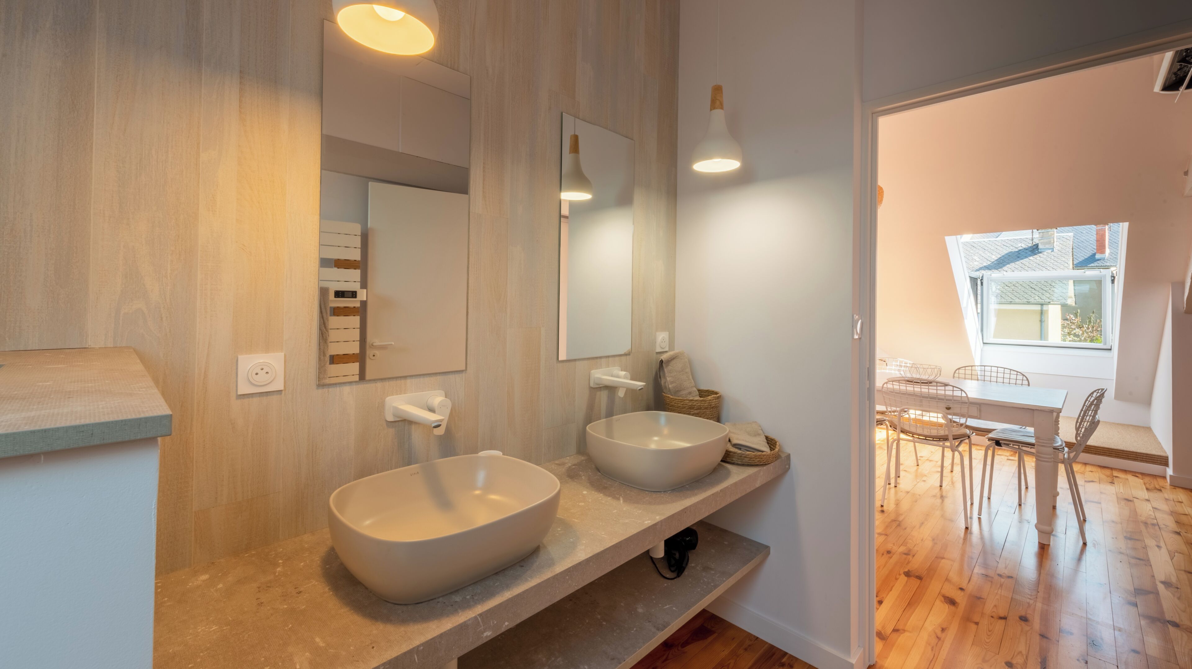 Un baño moderno con dos lavamanos grandes, un espejo y una ventana.