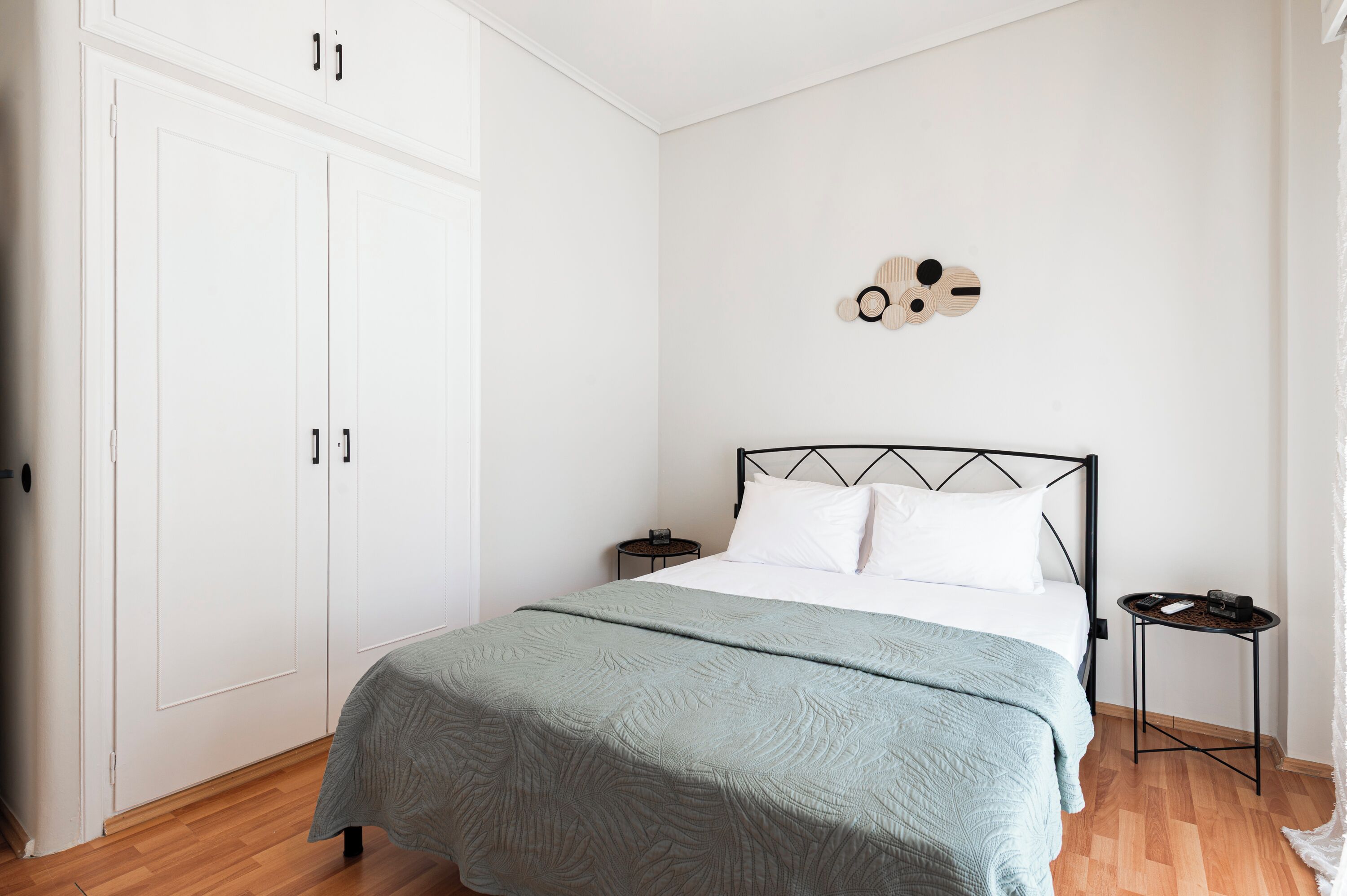 Una camera da letto con un letto, un armadio, un comodino e un elemento decorativo a parete.