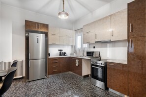 A modern kitchen with stainless steel appliances, wooden cabinets, and a granite countertop. - Glyfada Stay (Glifada)