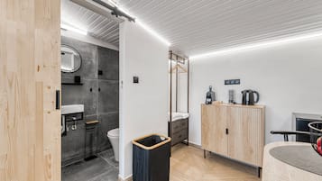 Un baño moderno con tocador de madera, un lavabo, un espejo, un perchero para toallas y un mueble con tetera.