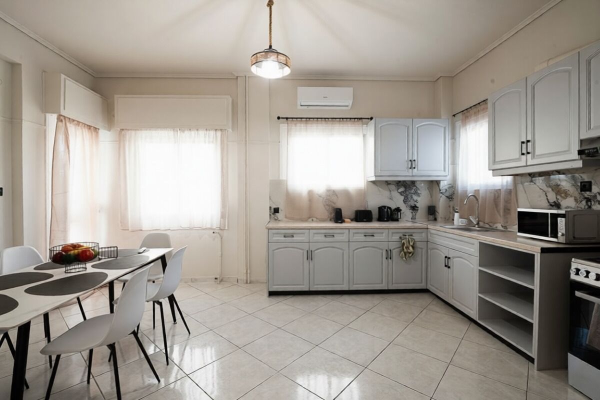 A modern kitchen with white cabinets, a dining table with chairs, and a microwave.