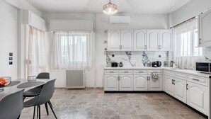 Een moderne keuken met witte kastjes, een marmeren spatwand en een eethoek met een tafel en stoelen.