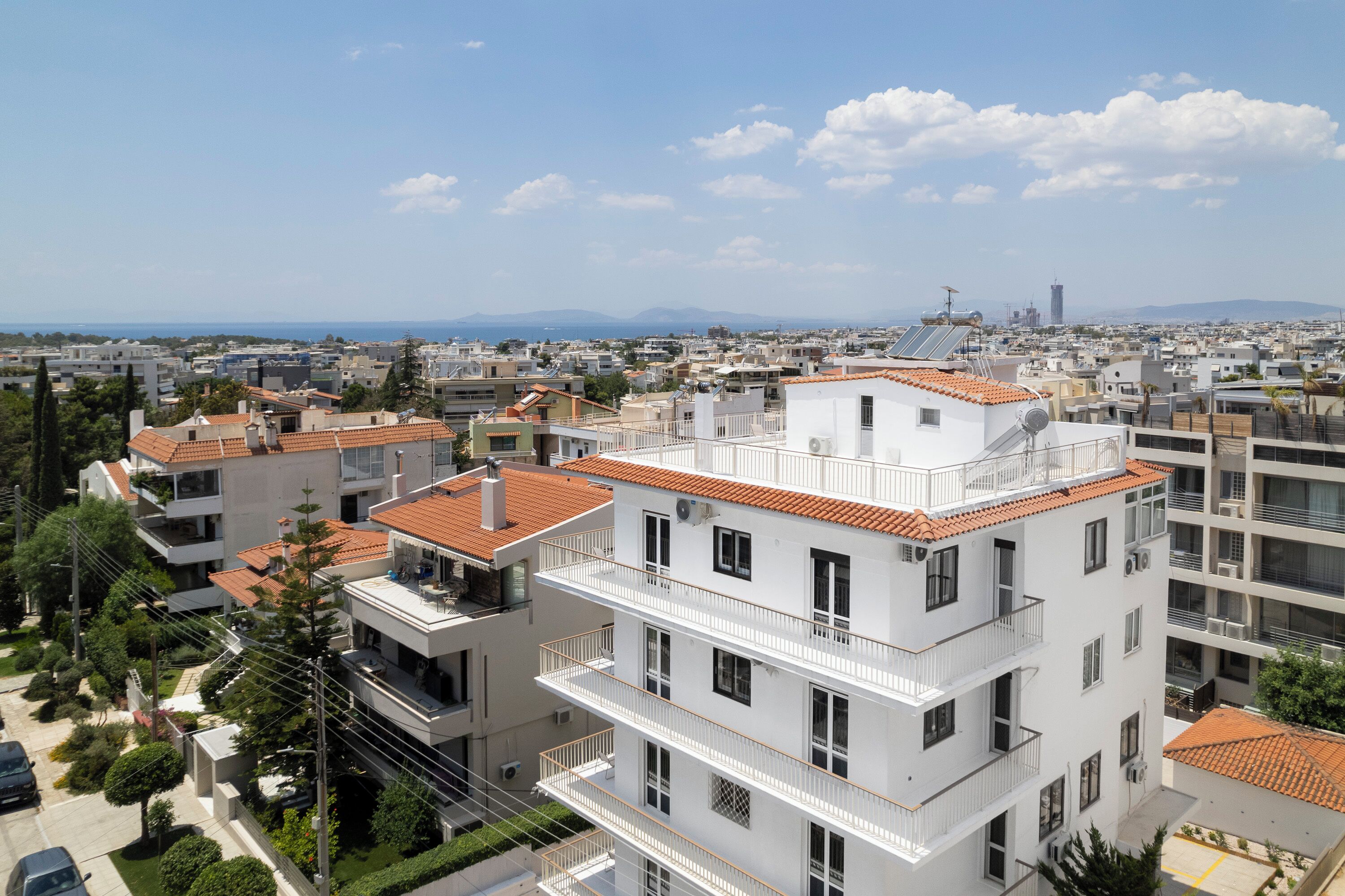 A multi-story residential building with balconies, a clear view of the cityscape, and a distant mountain range.