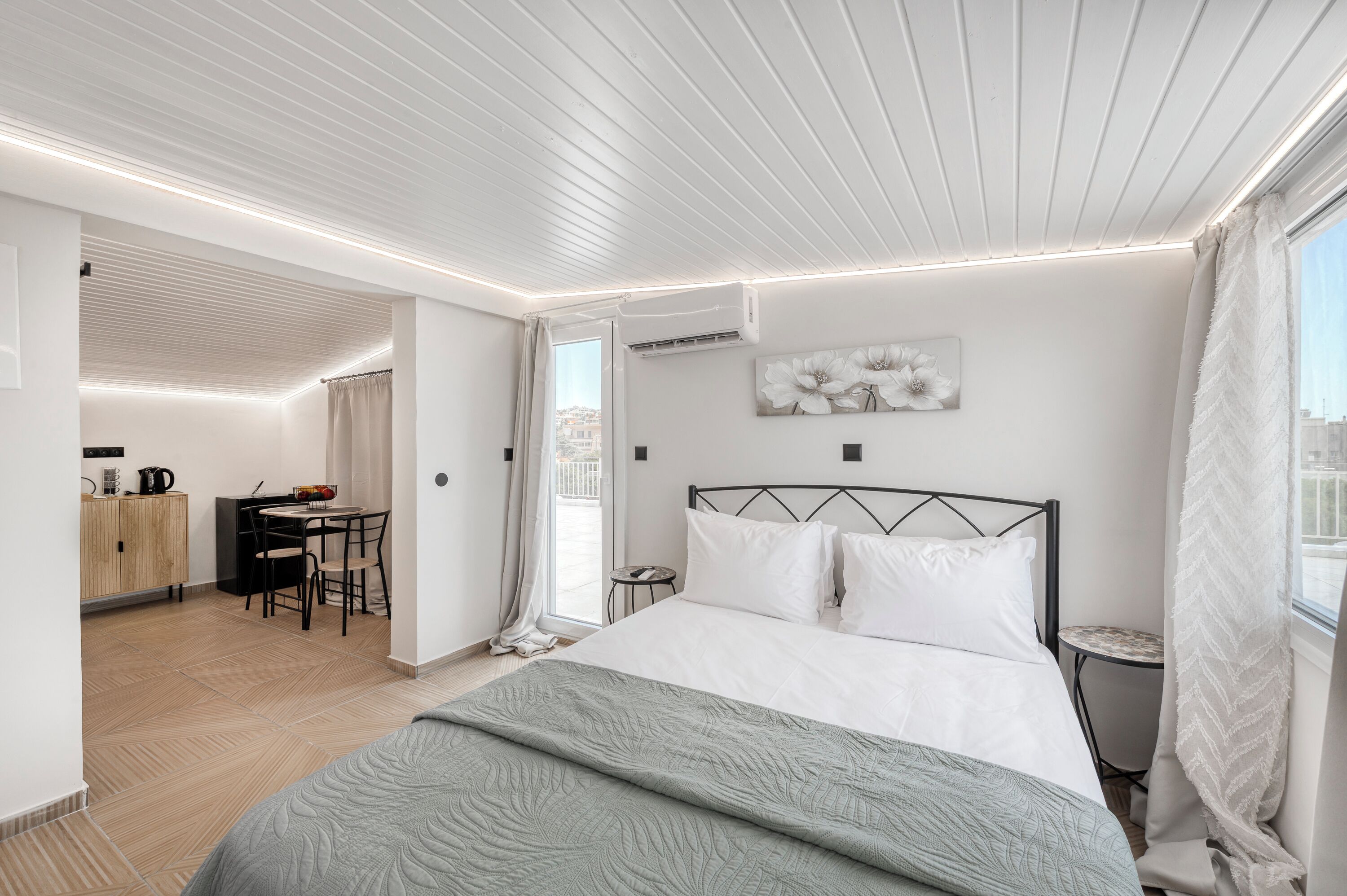 A modern bedroom with a bed, a desk, and a view of the city.