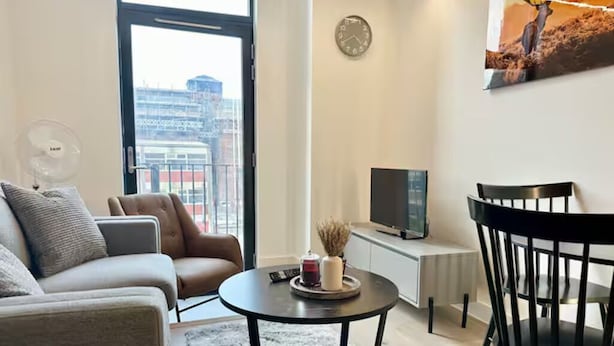 Ein modernes Wohnzimmer mit einer Couch, einem runden Couchtisch, einem Fernseher und einem Essbereich mit einem Stuhl.