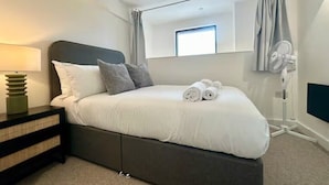 Ein Schlafzimmer mit einem Bett, einer Nachttischlampe, einem Spiegel und einem Deckenventilator.