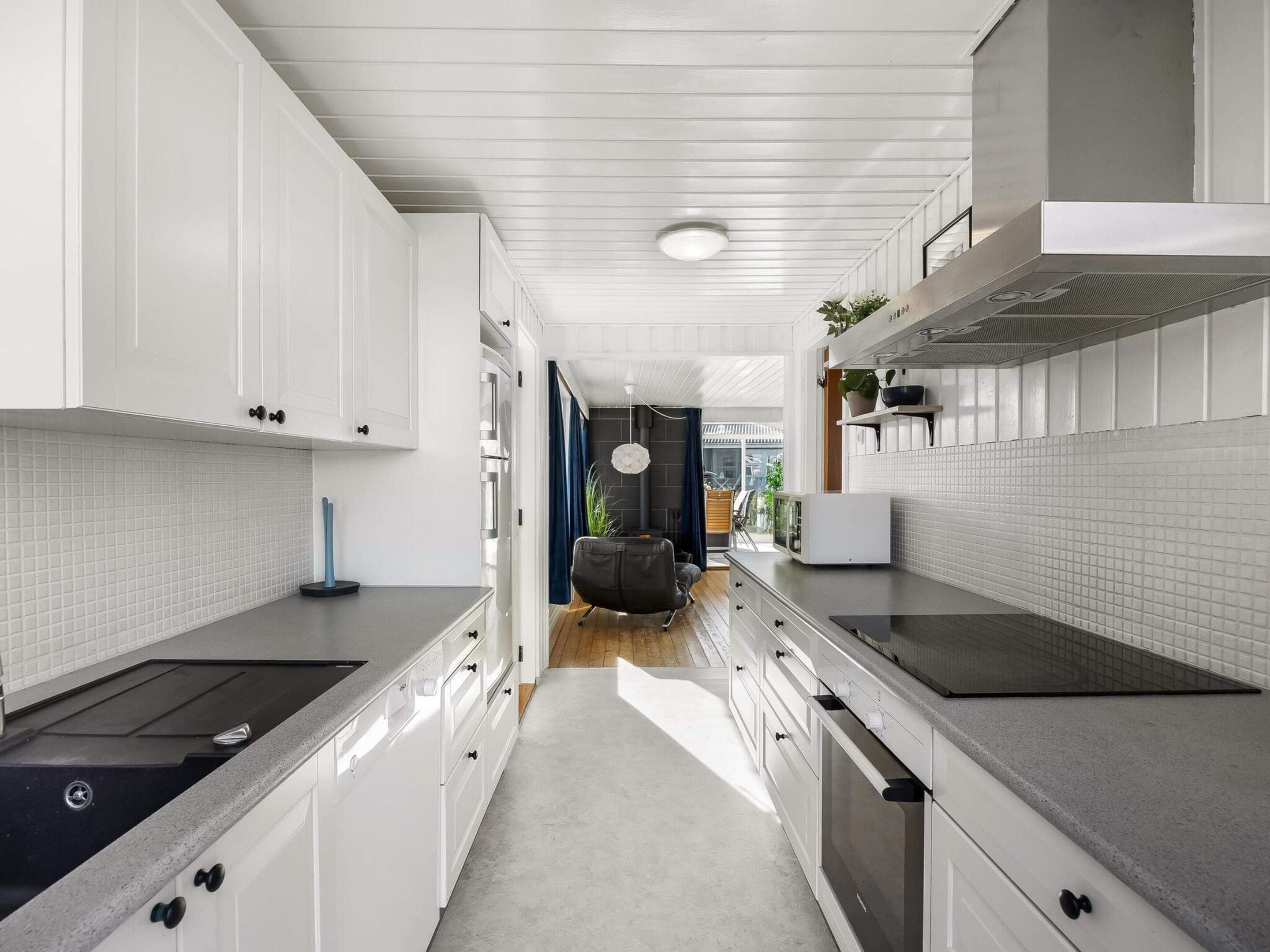 A modern kitchen with white cabinetry, a central island, and a view into the dining area.
