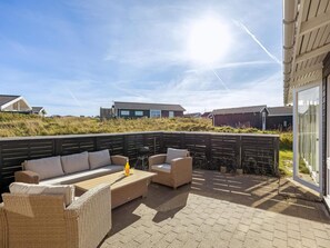 A patio area with outdoor furniture and a view of the surrounding landscape. - 4 Star Holiday Home in Lokken (Lokken)