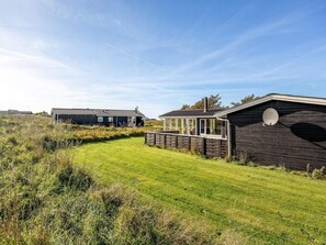 A modern vacation home with a large deck, a conservatory, and a well-maintained lawn. - 4 Star Holiday Home in Lokken (Lokken)