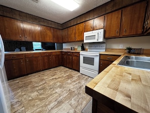 A kitchen with wooden cabinets, a microwave, an oven, and a sink. - Family-Friendly 4BR Getaway Close to Beaches, Fairhope & Fishing (Summerdale)