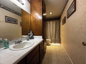 A bathroom with a double sink, a mirror, a clock, a toilet, and a shower curtain. - Family-Friendly 4BR Getaway Close to Beaches, Fairhope & Fishing (Summerdale)