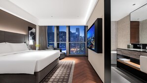 A modern hotel room with a large bed, a TV, a bathroom with a mirror, and a city view. - IntercityHotel Shenzhen Bay (Shenzhen)