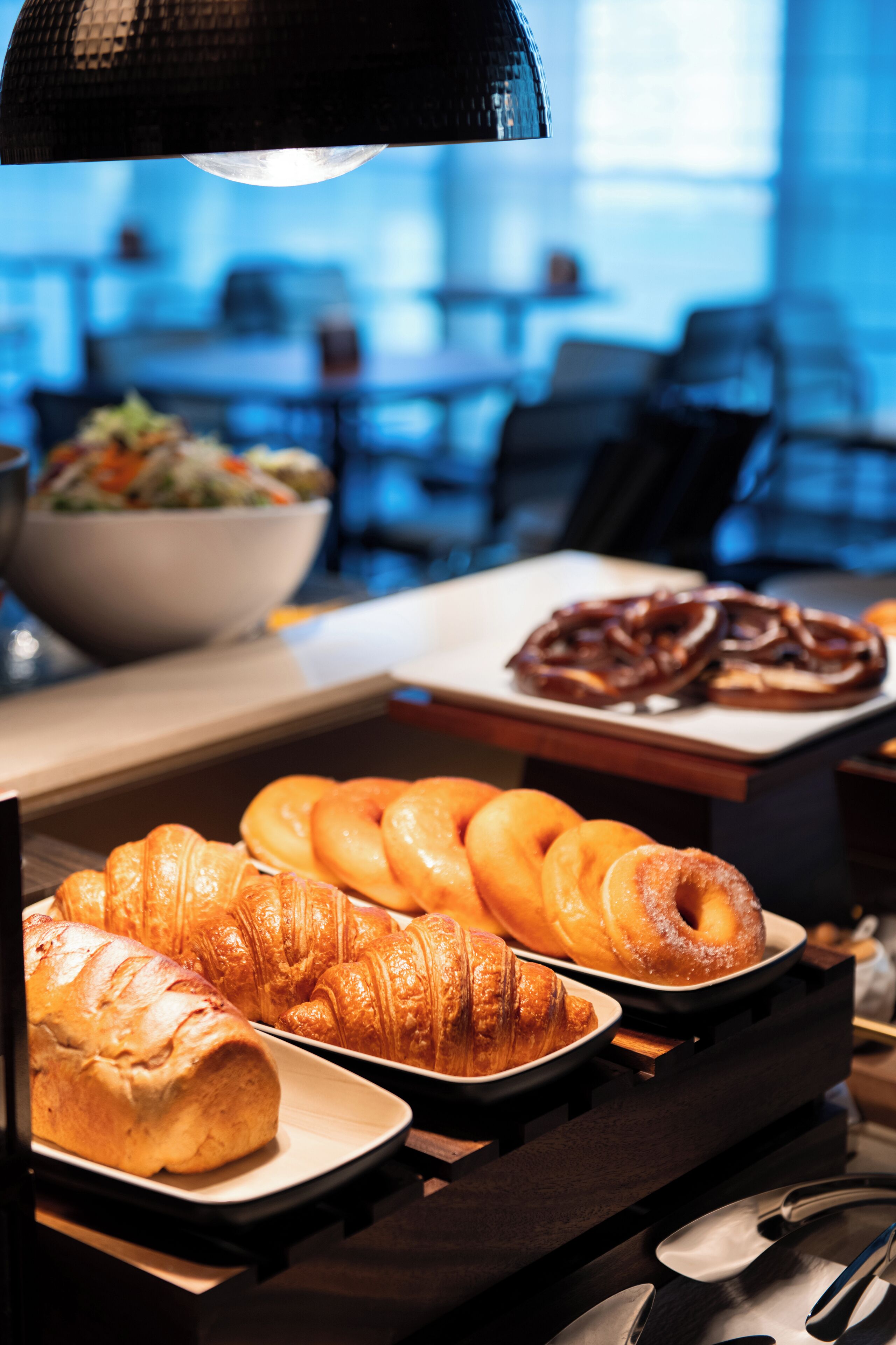 A buffet with pastries and a bowl of salad.