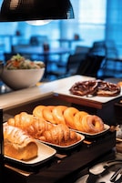 A buffet with pastries and a bowl of salad.