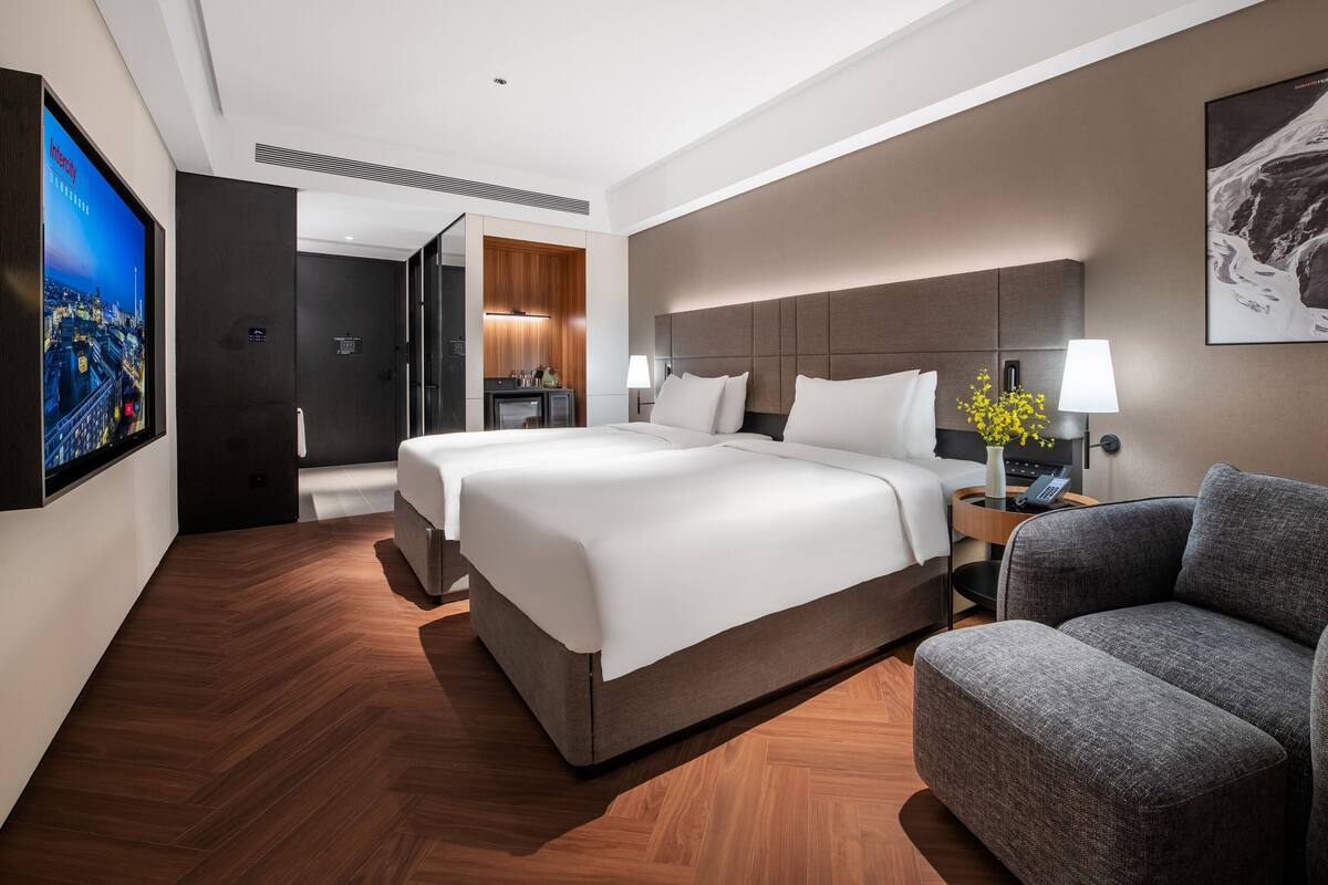 Ein Hotelzimmer mit einem großen Bett, einer Sitzecke, einem Fernseher und einem Bild an der Wand.