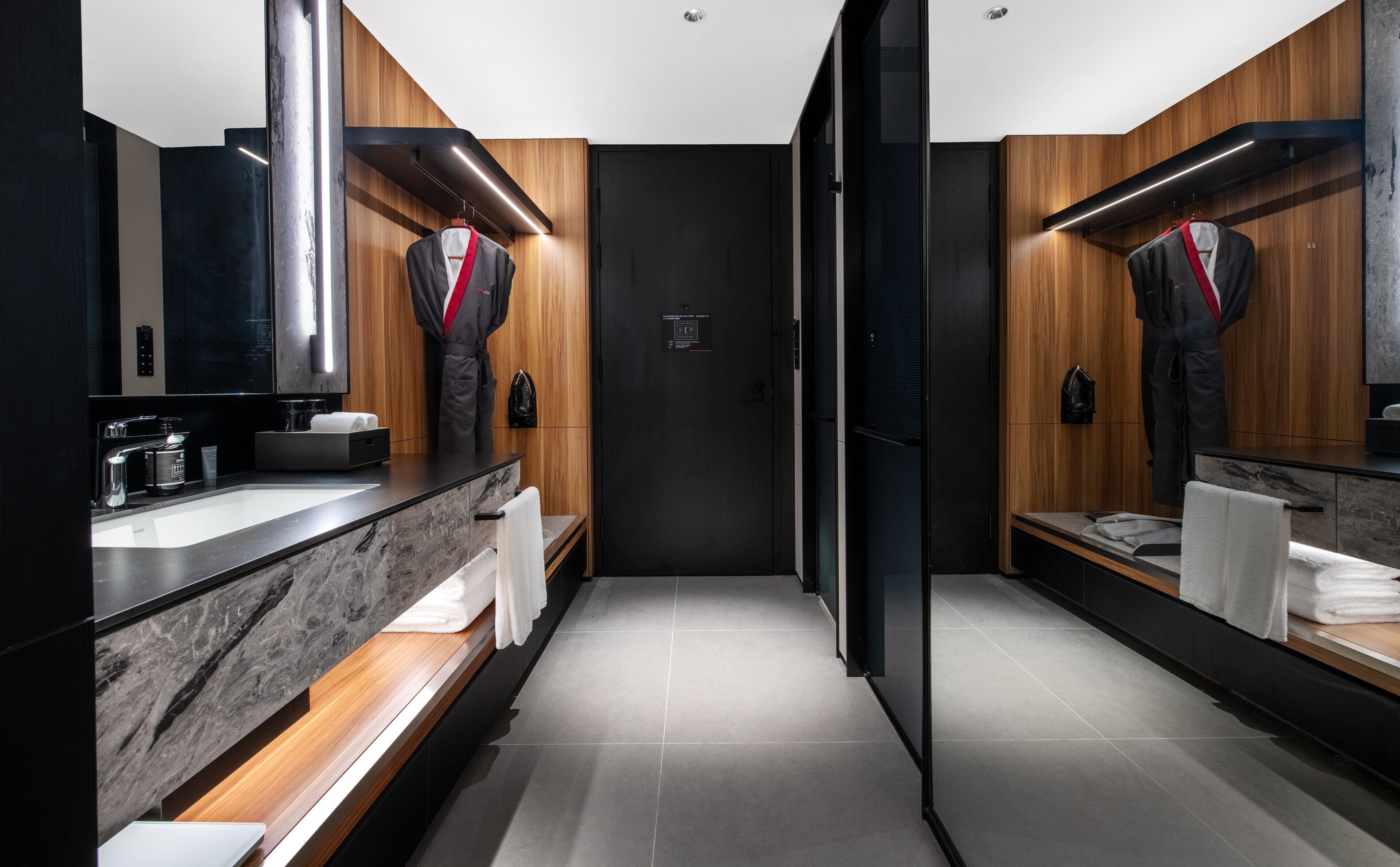 A modern bathroom with a marble sink, wooden vanity, and a large mirror.