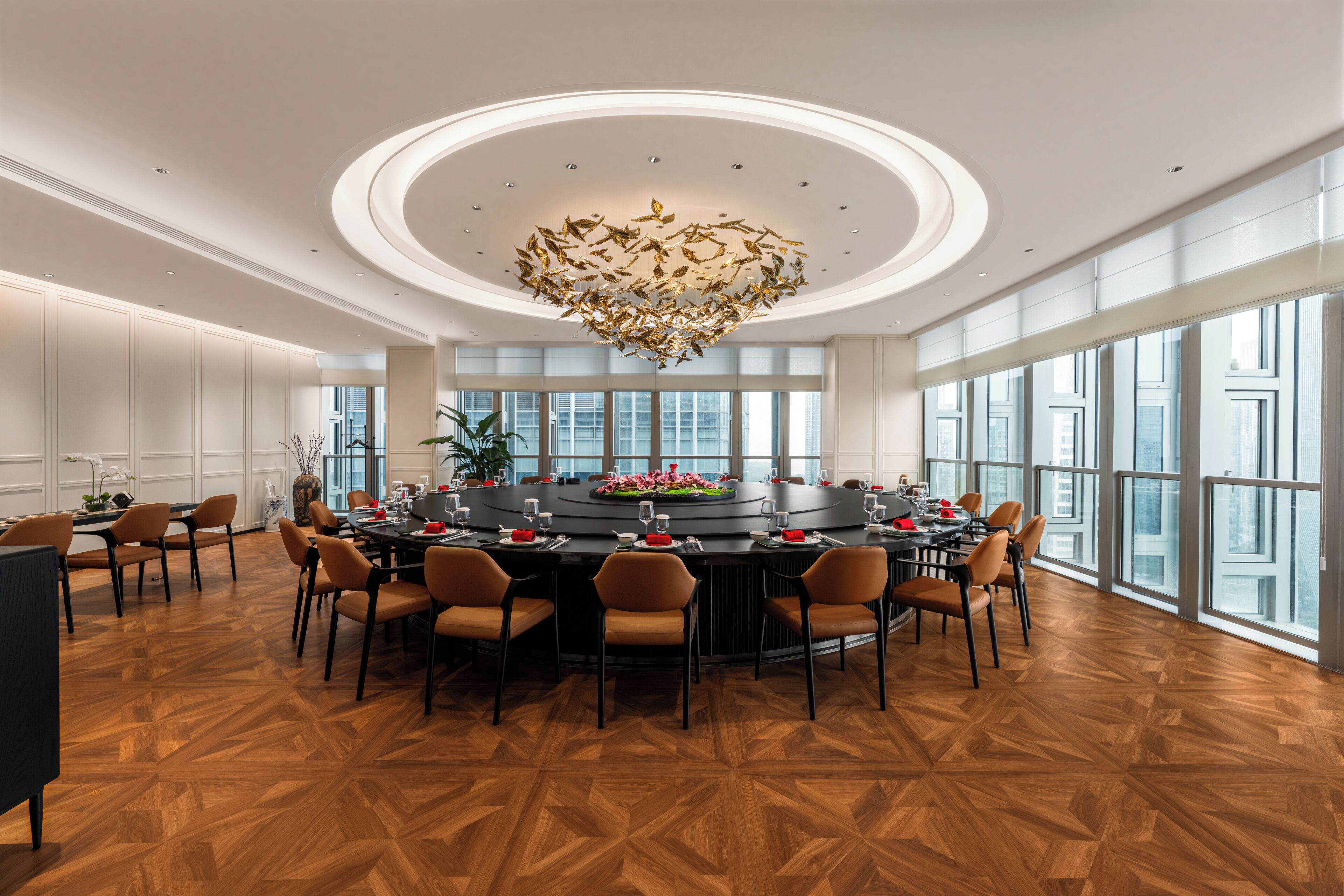 A spacious dining area with a round table, chairs, and a modern chandelier.