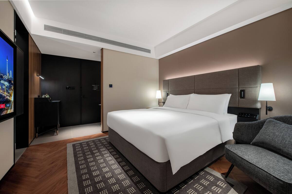 Ein modernes Hotelzimmer mit einem großen Bett, einer Couch, einem Fernseher und einem Schreibtisch.