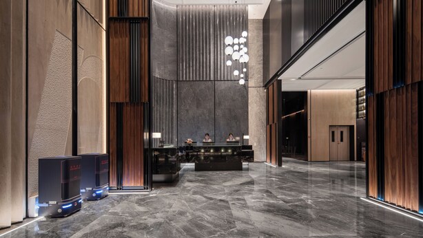 A modern reception area with a marble floor, a reception desk, and a vertical light fixture. - IntercityHotel Shenzhen Bay (Shenzhen)