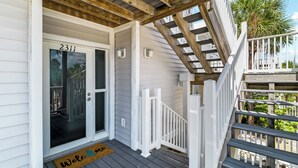 A wooden porch with a white door marked '2311' and a 'Welcome' mat.
