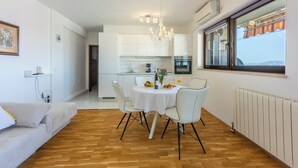 Una cocina moderna con armarios blancos, una araña y un comedor con mesa y sillas.