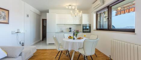 Una cocina moderna con armarios blancos, una araña y un comedor con mesa y sillas.