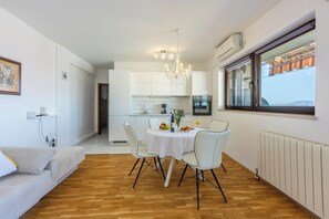A modern kitchen with white cabinets, a chandelier, and a dining area with a table and chairs. - Modern vacation apartment for 2 in the heart of Novi Vinodolski (Novi Vinodolski)