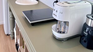 A kitchen with a white sink, a coffee maker, and a window with a view of greenery. - Escape to an adults only, coastal intimate retreat. (Hideaway Bay)