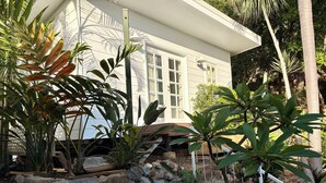 A house with a garden featuring various plants and a stone pathway. - Escape to an adults only, coastal intimate retreat. (Hideaway Bay)