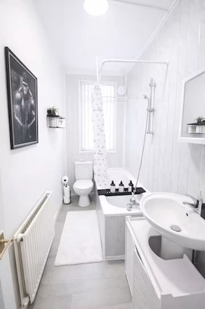 A modern bathroom with a toilet, bidet, bathtub, and a large sink. - 30% off Comfortable 4-Bed Home 8 Beds Pets Welcome Sleeps 9 (Leeds)