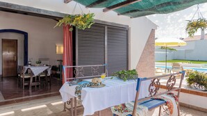 Eine Terrasse im Freien mit Tisch, Stühlen, einer Bank und einer hängenden Pflanze.
