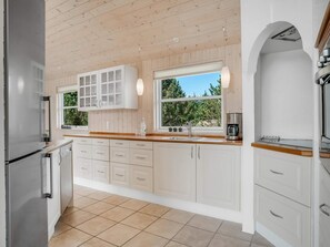 Eine moderne Küche mit weißen Schränken, einem Edelstahlkühlschrank und einer Kaffeemaschine.