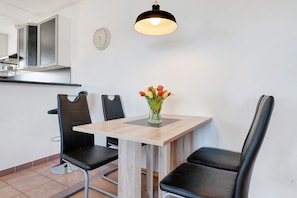Un coin repas avec une table en bois, des chaises noires et un vase rempli de fleurs.