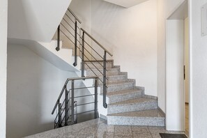Una escalera con barandales de metal y peldaños de granito.