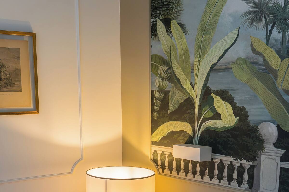 Une chambre d’hôtel avec un lit, des oreillers, une table de chevet avec une lampe et un tableau au mur.