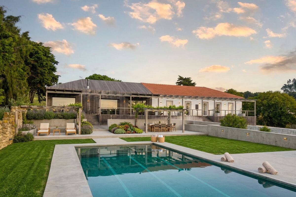 Une maison moderne dotée d’une piscine, d’un espace salon extérieur et d’un patio couvert.