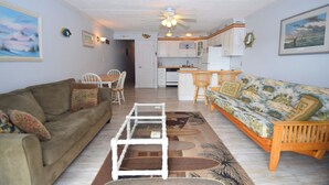 A living room with a sofa, a coffee table, and a dining area with chairs. - Eldorado 2 - Ocean City, MD (Ocean City)