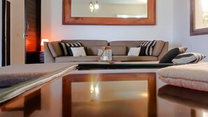 A room with a sofa, a table, a mirror, and a window.