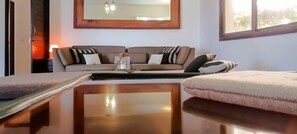 Une pièce avec un canapé, une table, un miroir et une fenêtre.