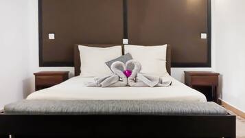 A neatly made bed with pillows, a bedside table, and a headboard.