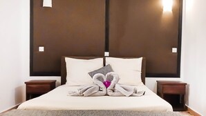 A neatly made bed with pillows, a towel, and a decorative item in the center. There are two bedside tables with lamps.
