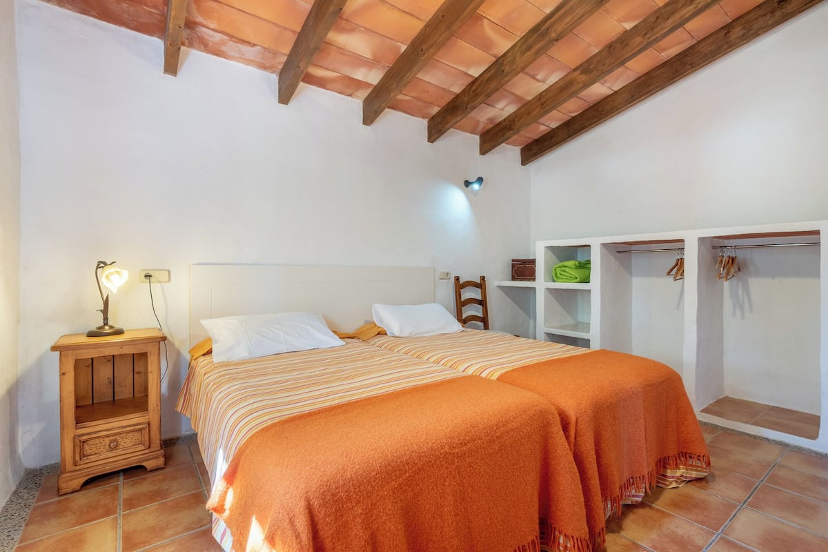 Un dormitorio con cama, mesita de noche, lámpara, armario y estantería.