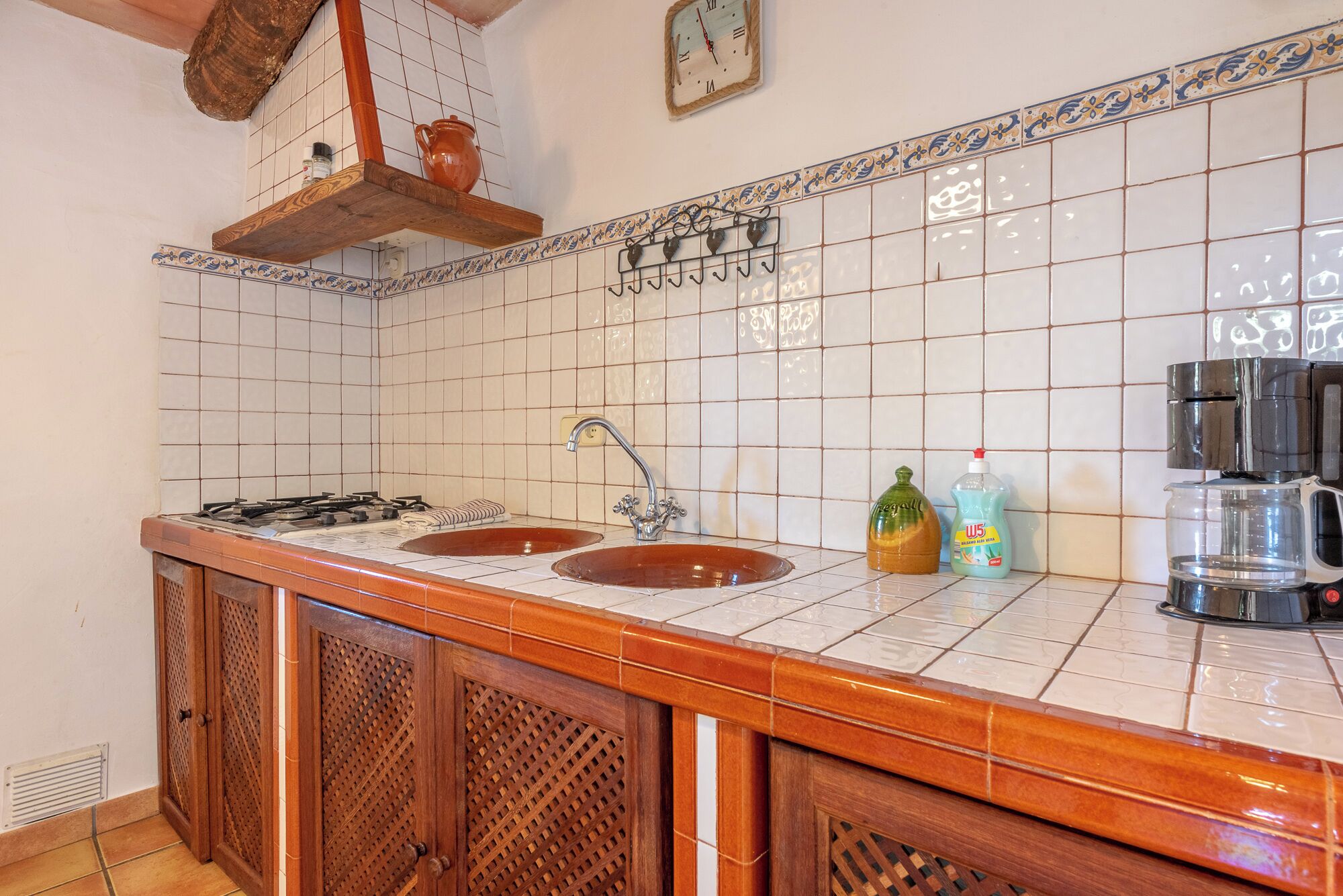 A kitchen with two sinks, a stove, and a coffee maker.