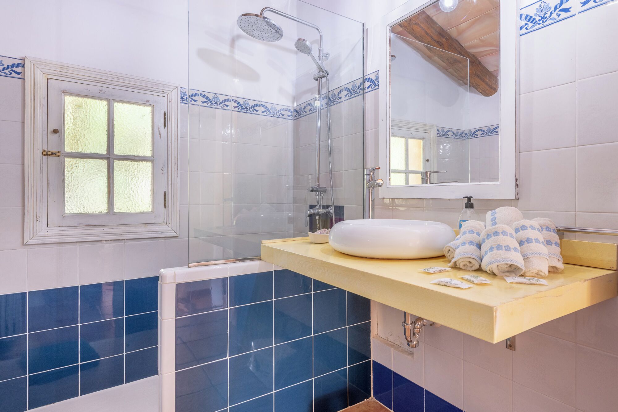 Ein Badezimmer mit Dusche, Waschbecken und Spiegel sowie einem Fenster.