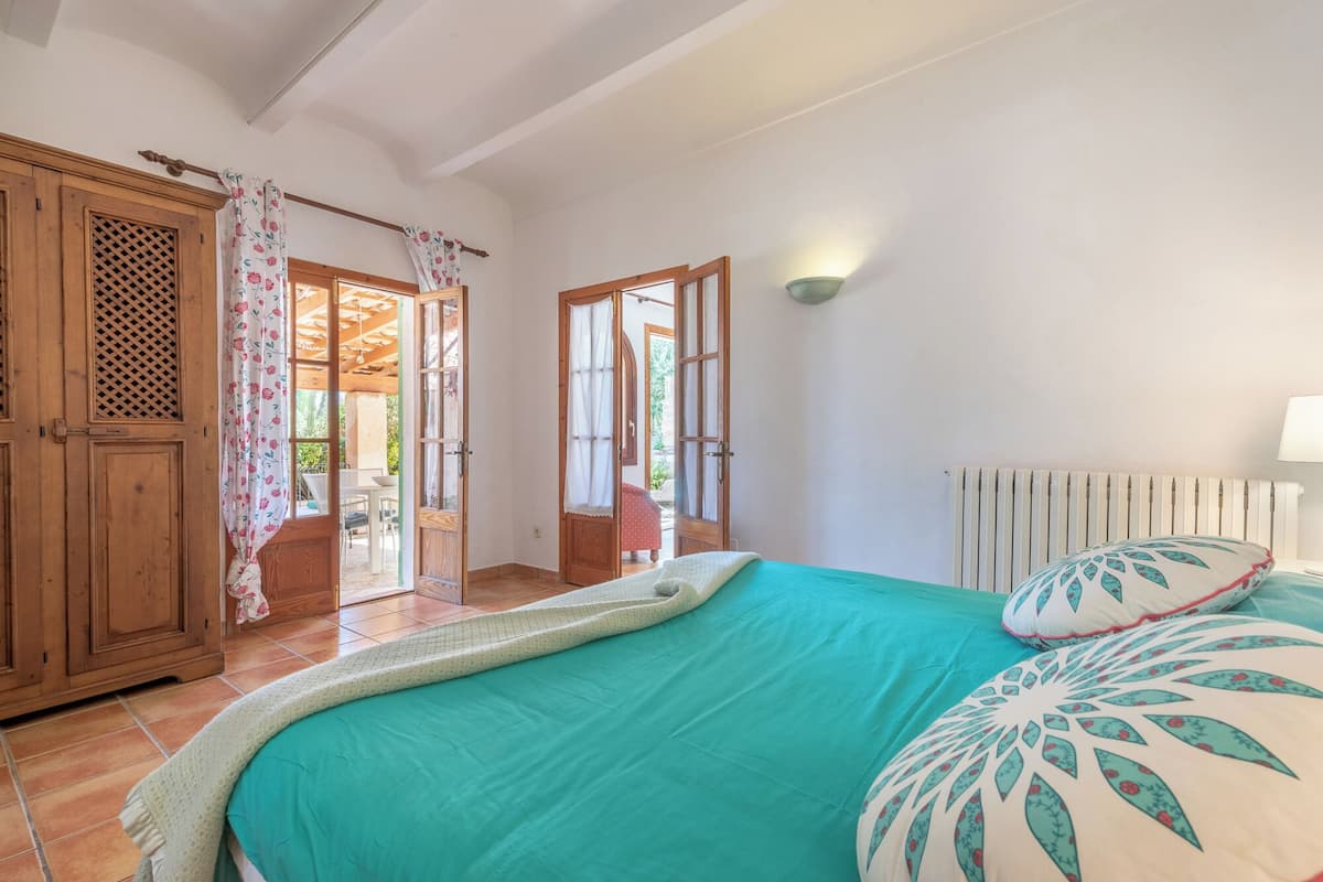 Un dormitorio con cama, radiador, ventana y puerta.