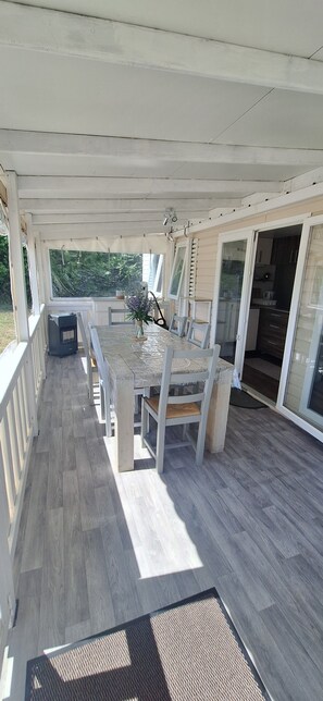 Un patio techado con mesa y sillas, una parrilla y vistas al exterior.