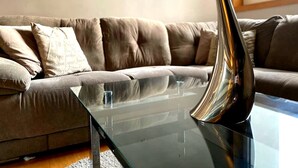 Un salon moderne avec une table basse en verre, un canapé en cuir marron et un coussin décoratif.