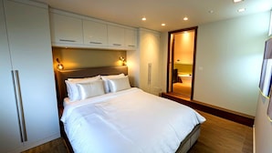 Une chambre d’hôtel moderne avec un grand lit, une armoire intégrée et une petite salle de bain.